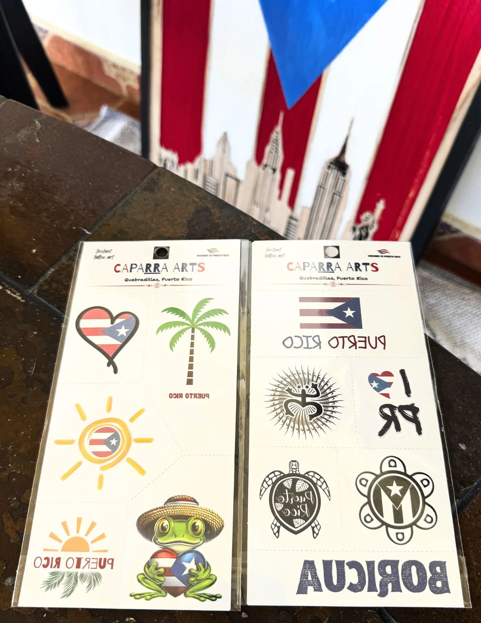 Caparra Arts tattoo sheets in front of a Puerto Rican flag painting